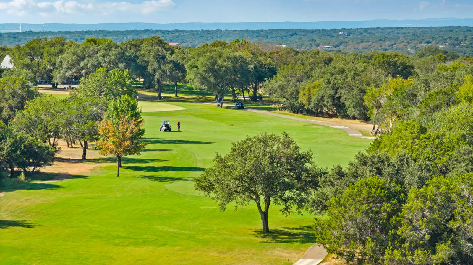 Golfers on an oak-lined fairway at Delaware Springs Golf Course in Burnet