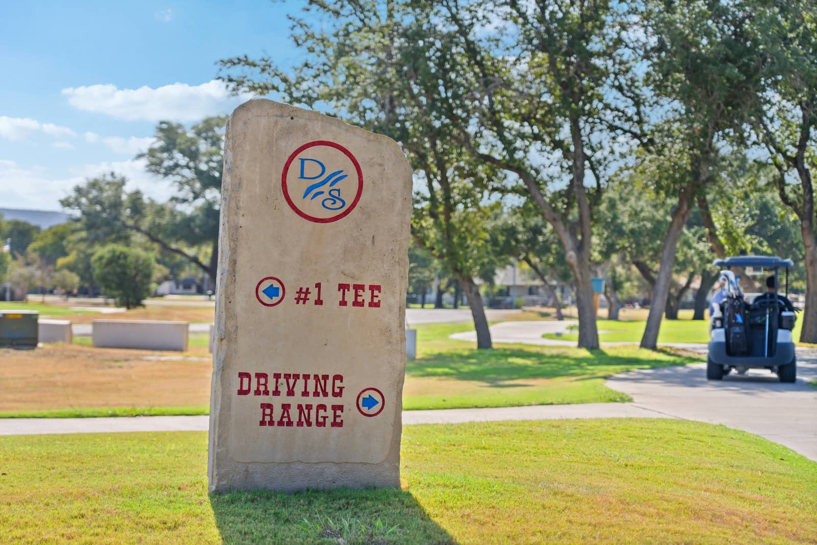 Stone first-tee and driving-range marker beside the cart path at Delaware Springs