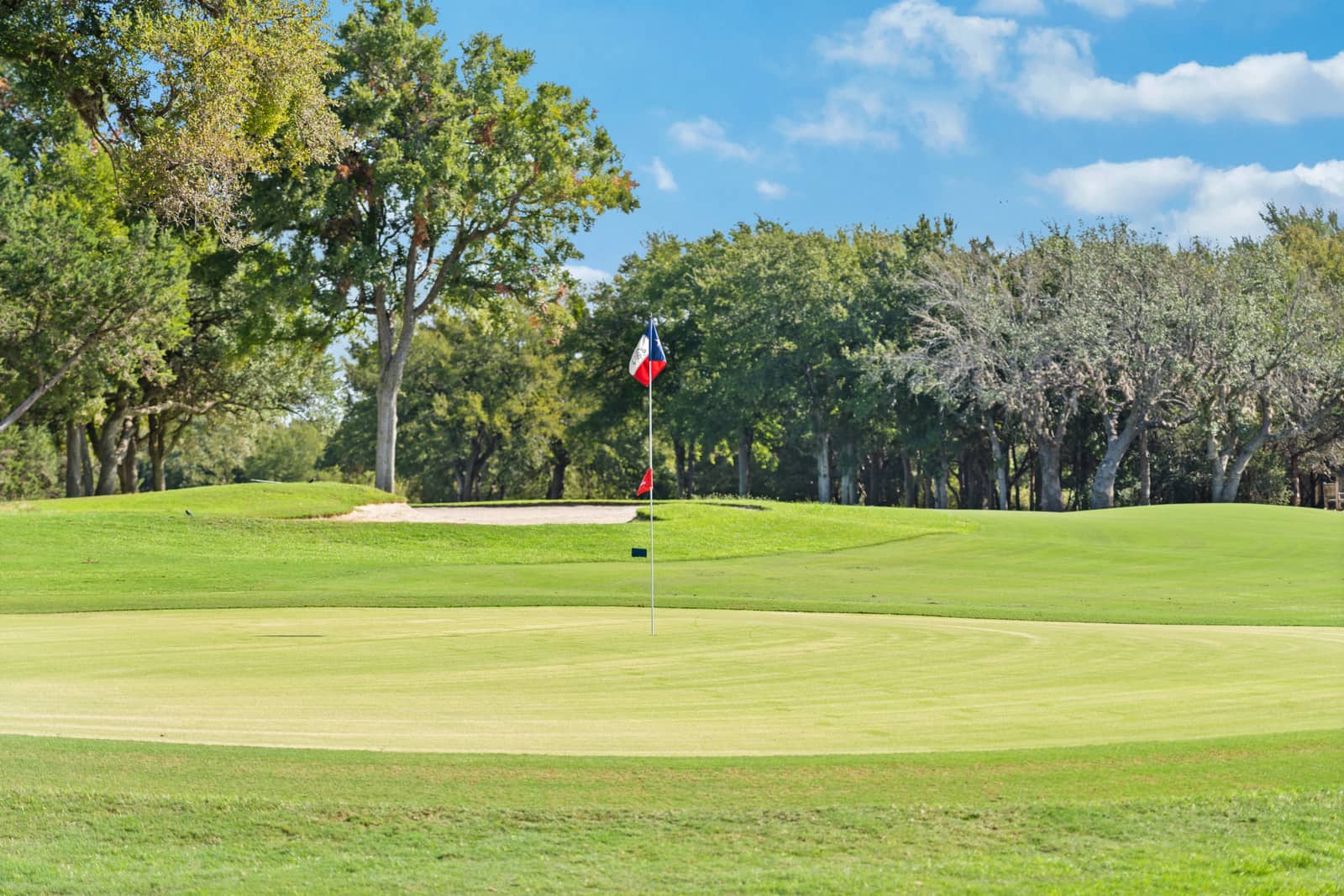 Texas flag marking a sunlit green at Delaware Springs Golf Course in Burnet
