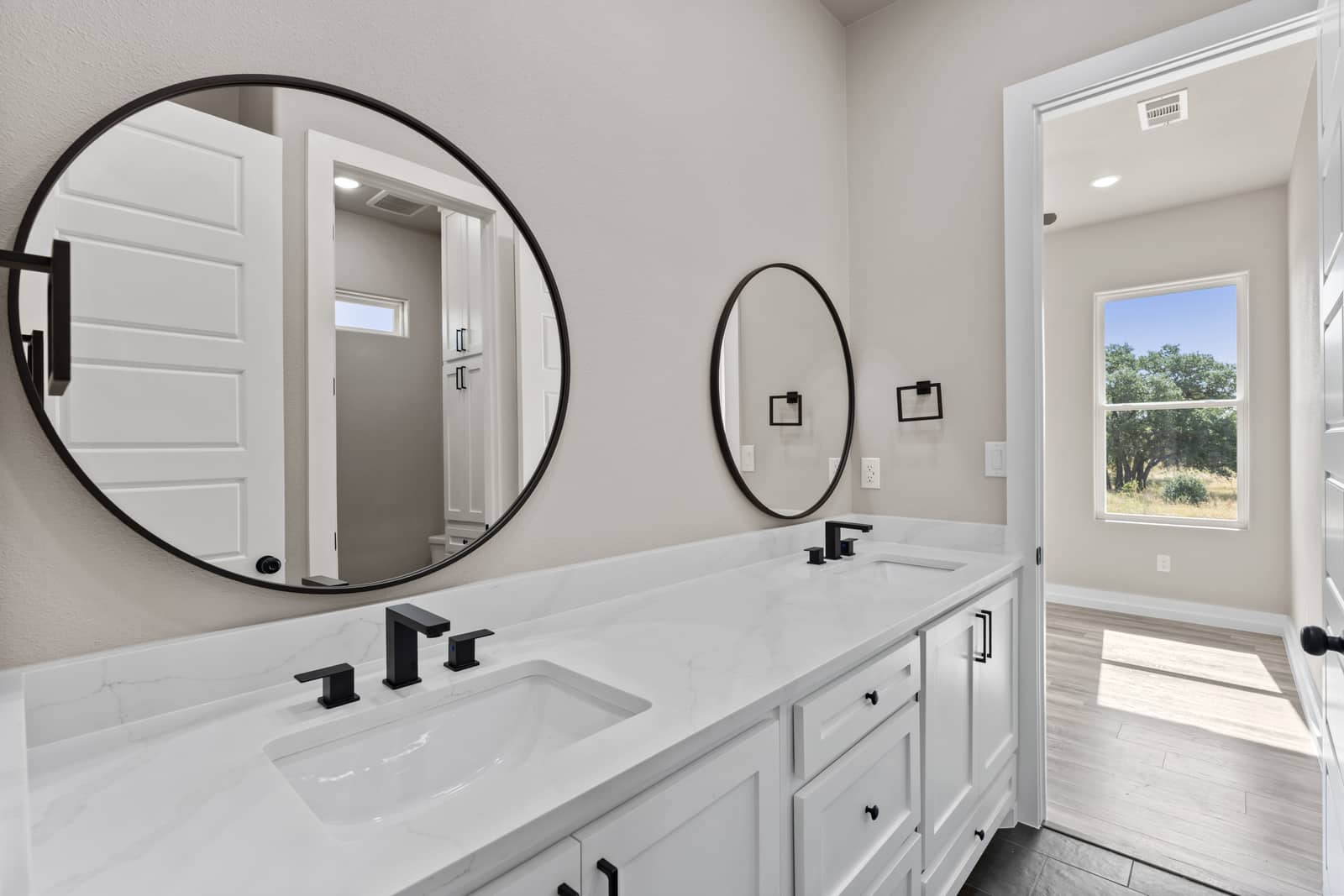 Bathroom with paired round mirrors and a double vanity at 258 Sunday Drive
