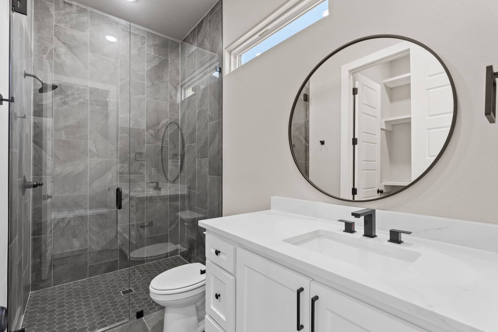 Bathroom with a round mirror and tiled walk-in shower at 258 Sunday Drive