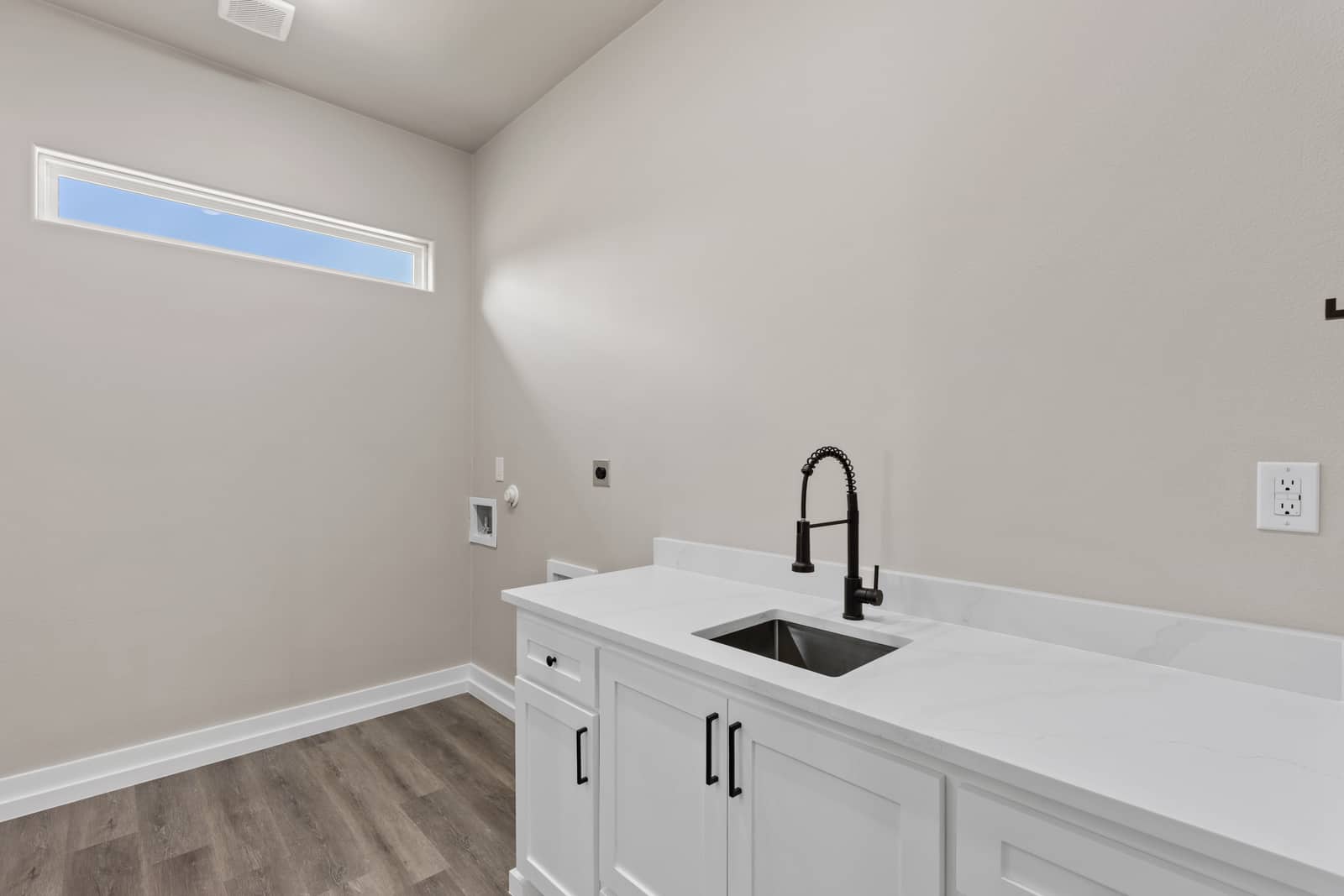 Laundry room with a sink, white cabinets and a high window at 262 Sunday Drive