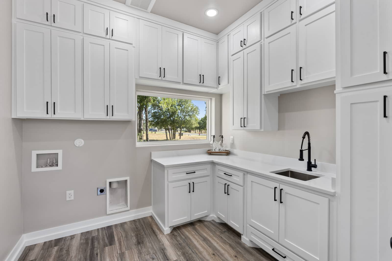 Laundry room with a sink, white cabinets and a window at 271 Sunday Drive