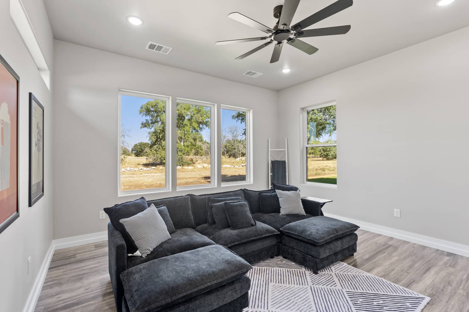 Sitting room with a dark sectional and three windows at 271 Sunday Drive